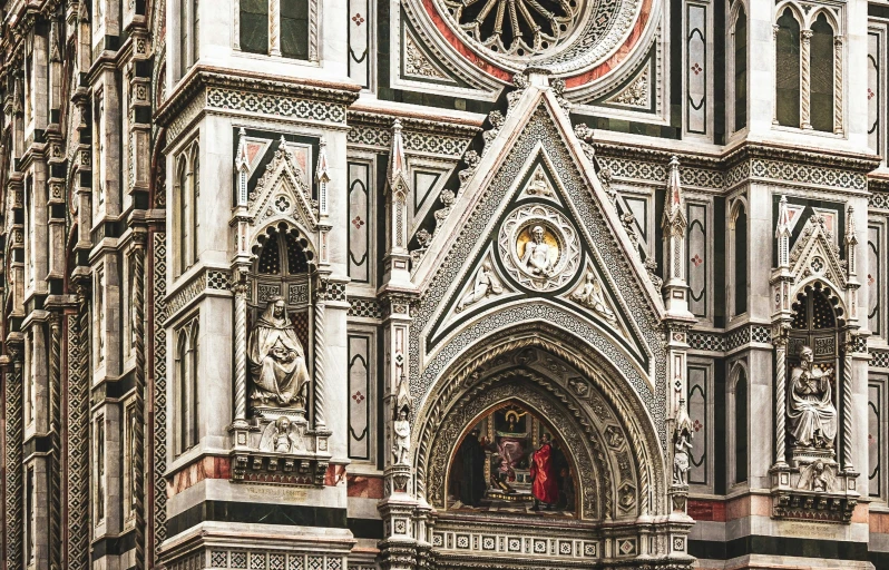 an old gothic style building has a small statue on the front