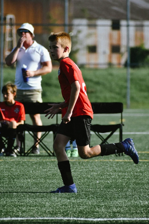 a small boy wearing a red shirt is in action on the soccer field