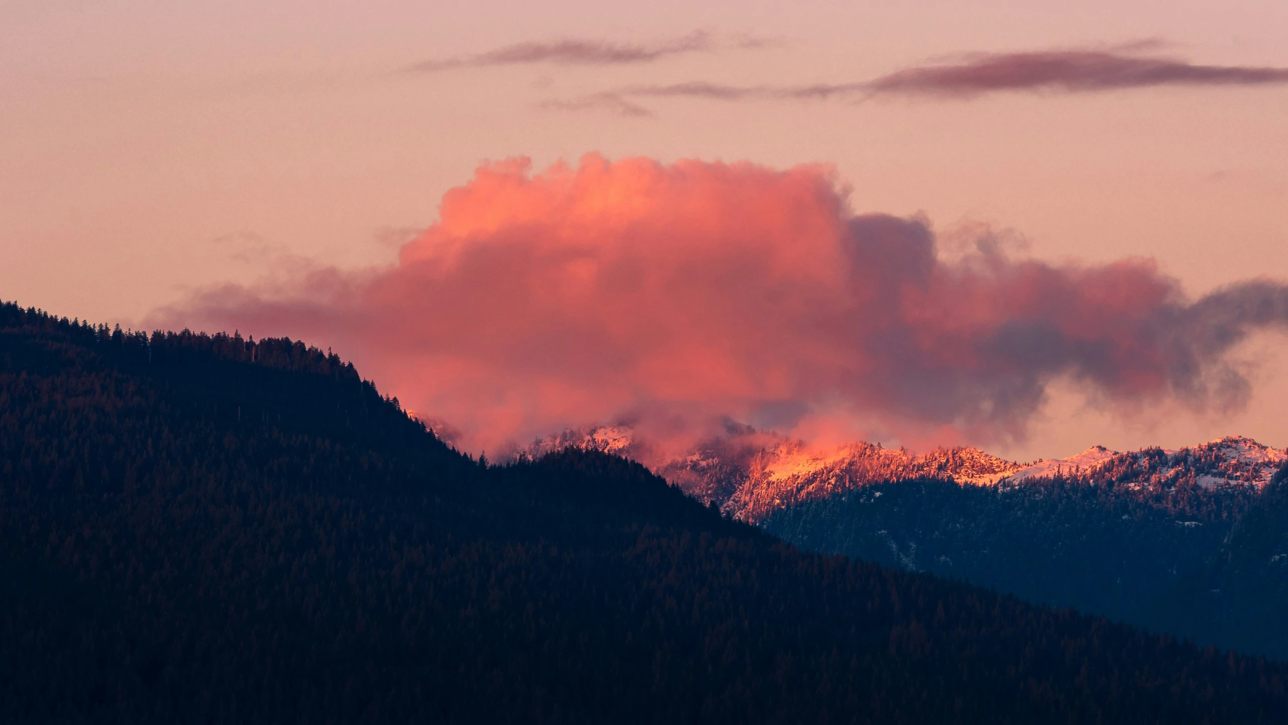 the sun rises behind the mountains covered with snow