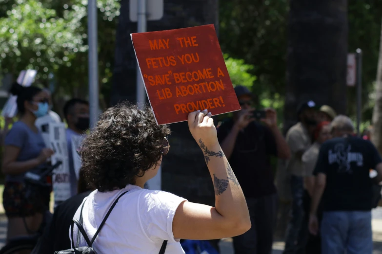 a person holding a sign in the street with a lot of people