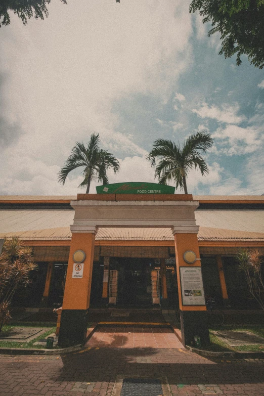 the front entrance of a public building with palm trees