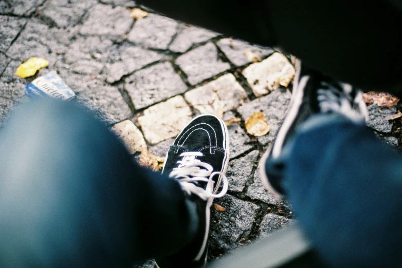 a person's feet wearing black and white sneakers with their pants blue and gray