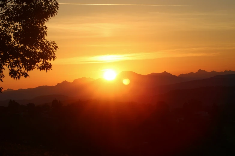 the sun rises behind some mountains during a sunny day