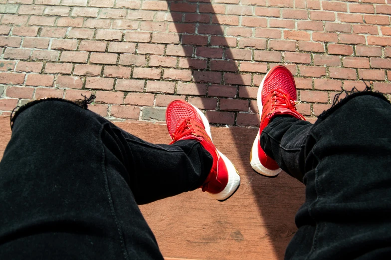 two persons wearing red sneakers and black pants