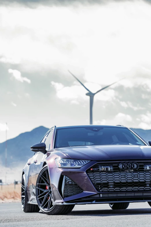 an audi coupe on a cloudy day in front of windmills