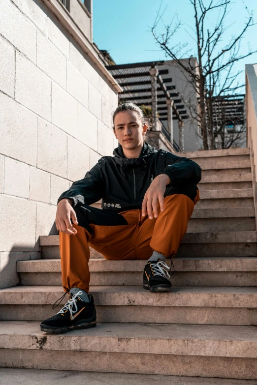 a man sits on stairs wearing a black jacket