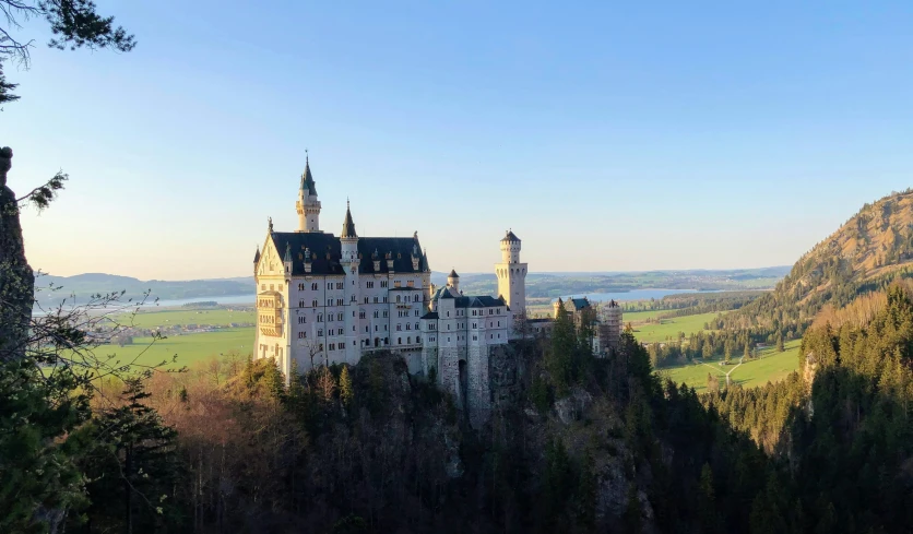 a castle in the middle of trees, overlooking a valley