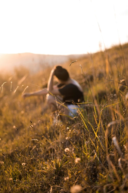 a young woman sits in the middle of a field