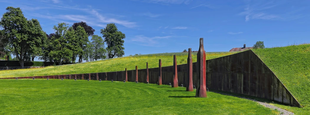 a line of poles and poles lined up next to the grass