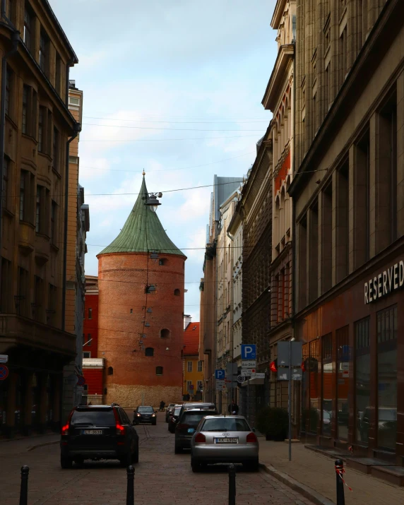 several cars are lined up on the street in front of many buildings