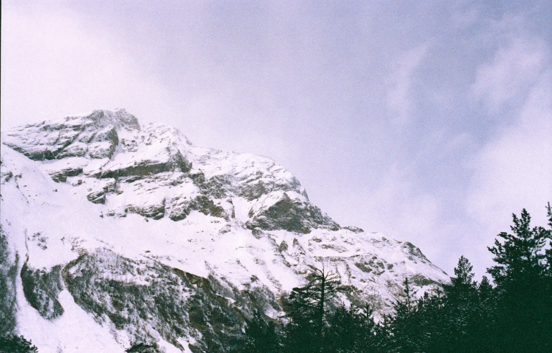 a snow covered mountain top on a cloudy day