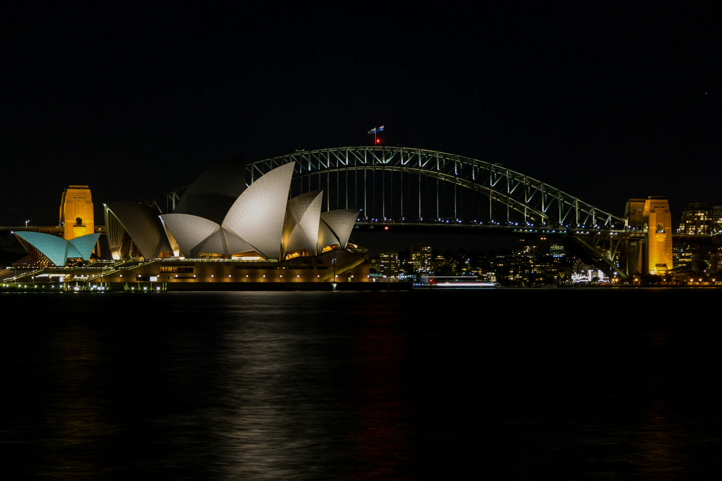 the sydney bridge and opera house lit up at night