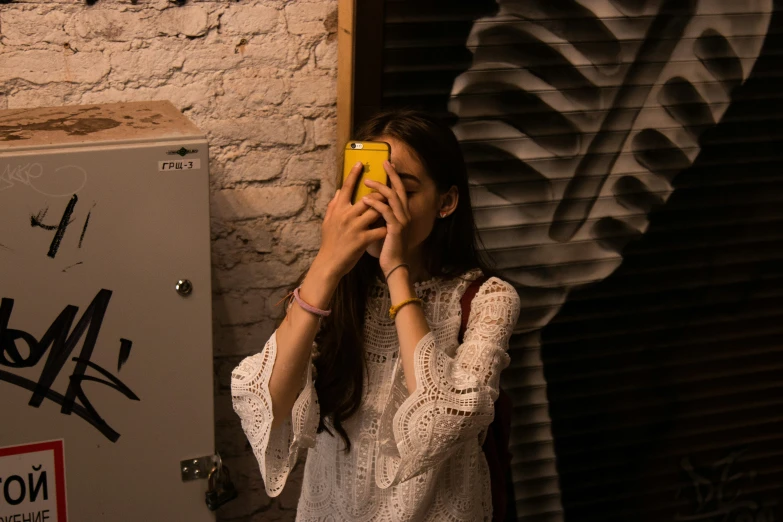 a girl with a phone near graffiti on a wall