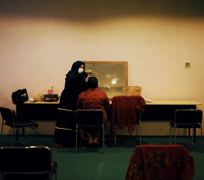 two women are sitting at a table with chairs and a mirror