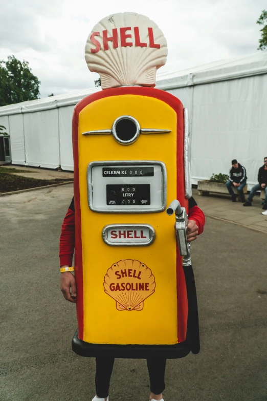 a man holding an old style shell gas pump