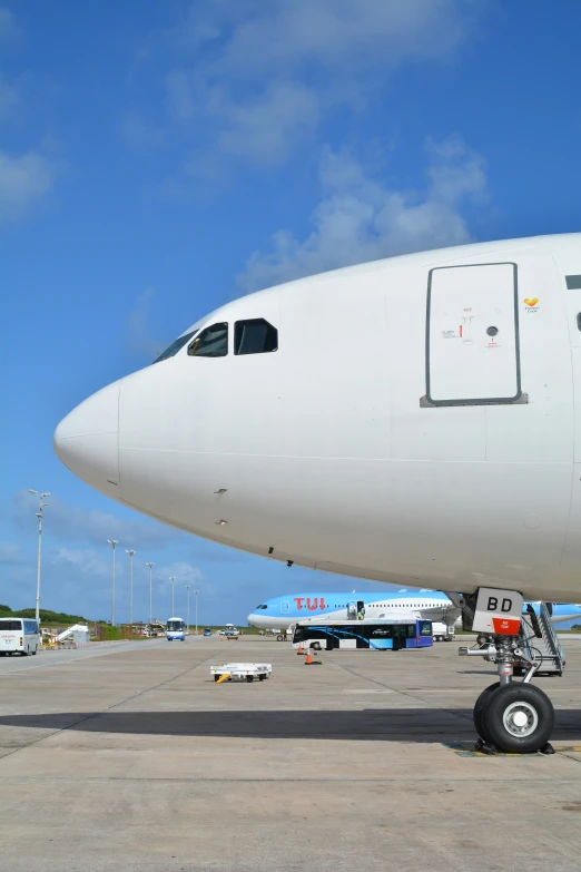 airplane sitting on tarmac under blue sky with clouds