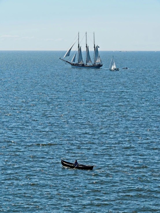 two boats and three sailing vessels in a body of water