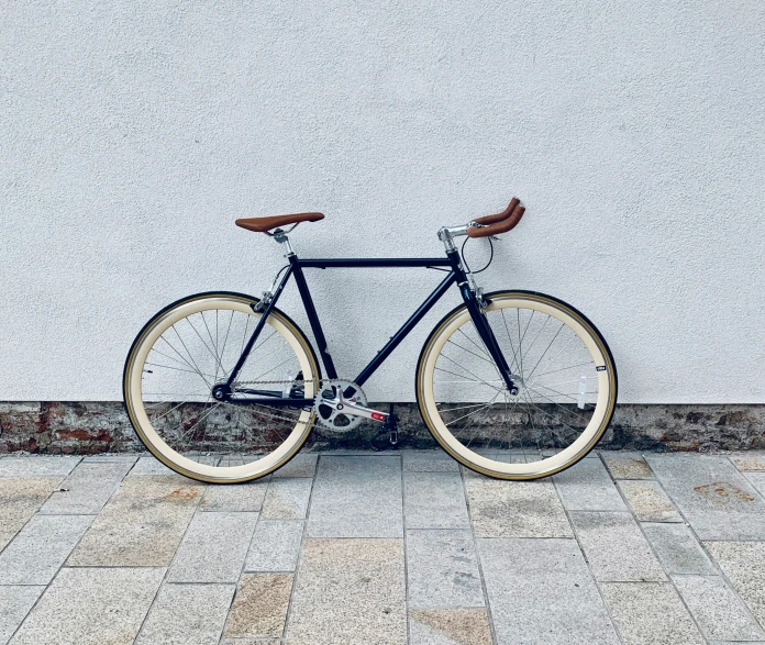 a black bicycle parked on the side of a white wall