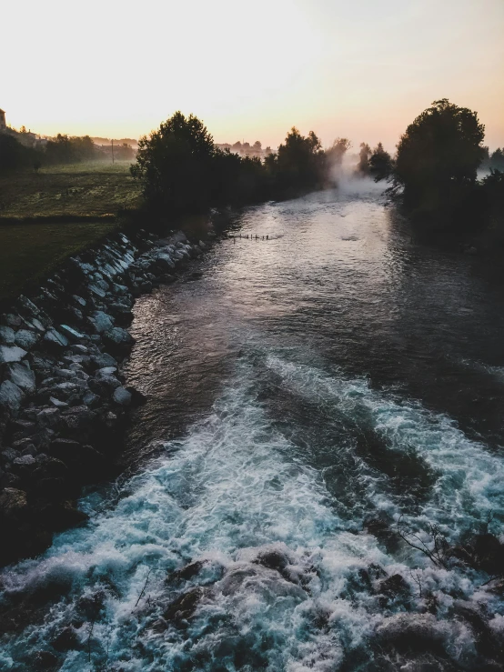 the sun sets on the river flowing into the water