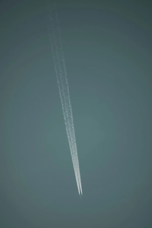 an airplane flying very high in the sky leaving a trail of smoke behind it
