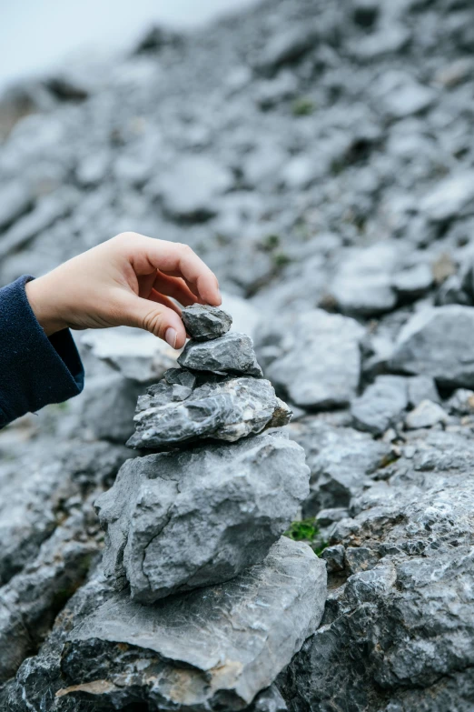 a person holding onto some rocks on a hill