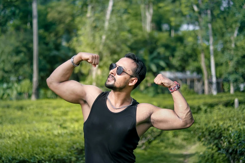 a young man flexing his muscles on a path in a lush green park