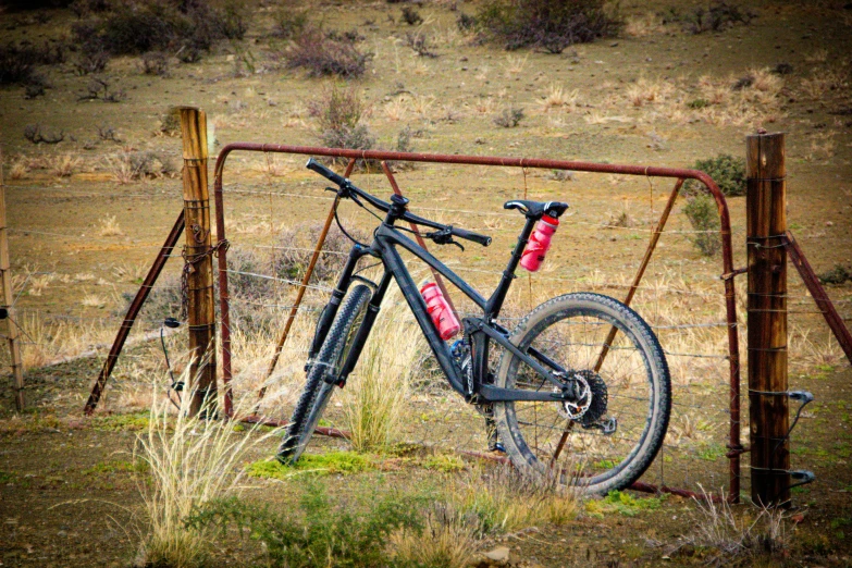 a bike resting on an old rusted gate in a pasture