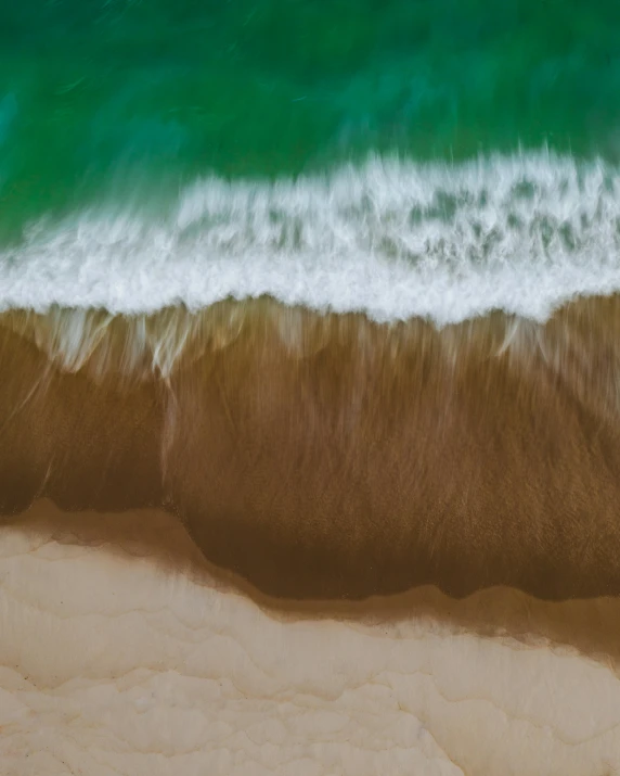 a wave rolls onto the sand at the ocean shore