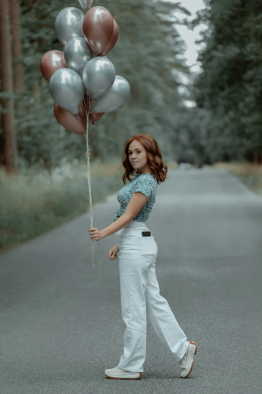 a woman holds a balloon and walks down a street