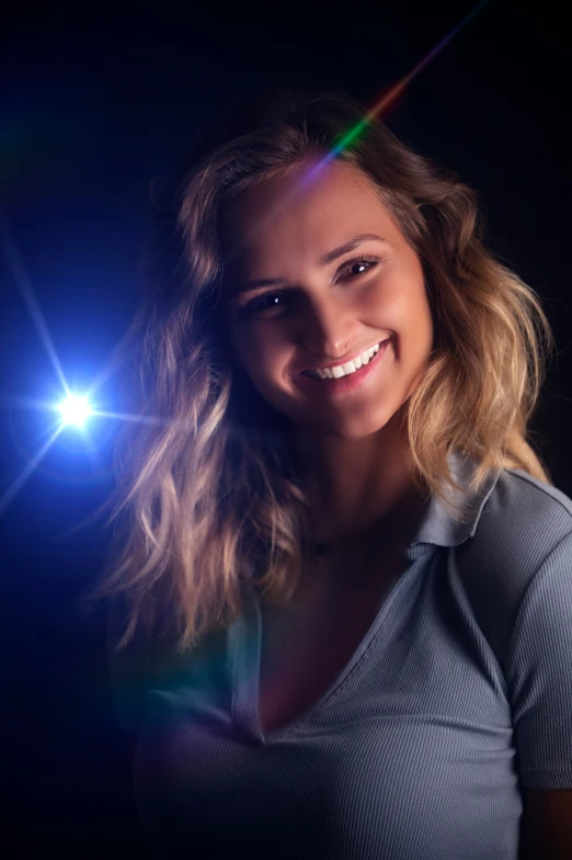 woman smiles while she is holding up a lit flashlight