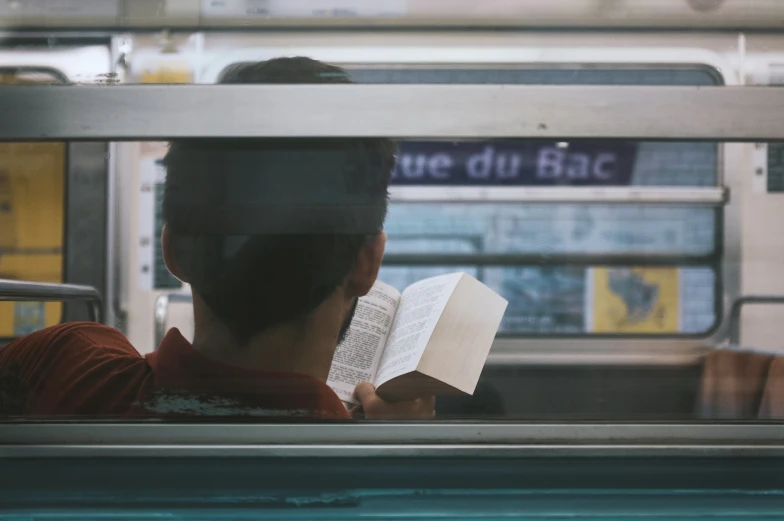 a man reading a book while riding the subway