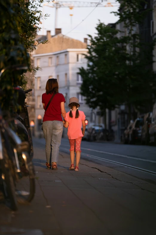 two people walking on the sidewalk as the sun sets