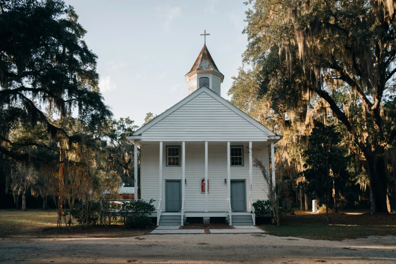 the white wooden church is in the middle of trees