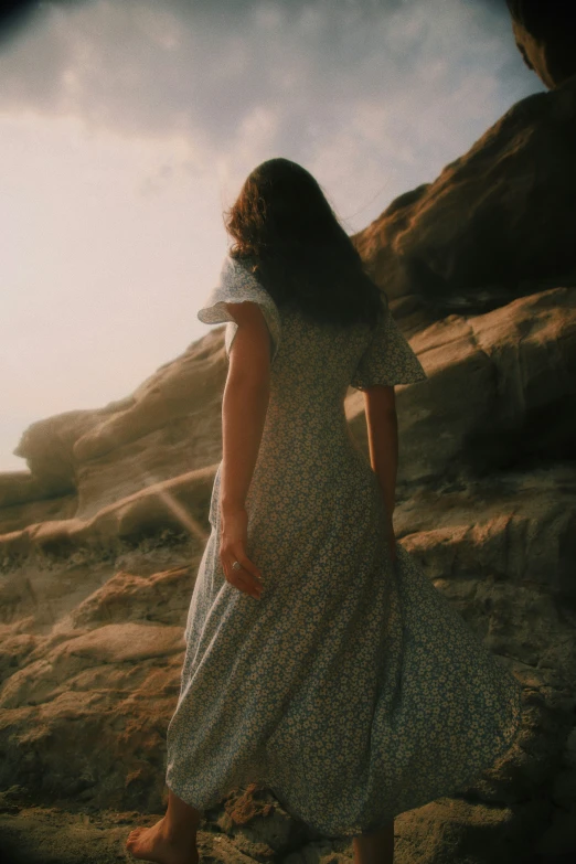 the girl is walking along the rocky shore