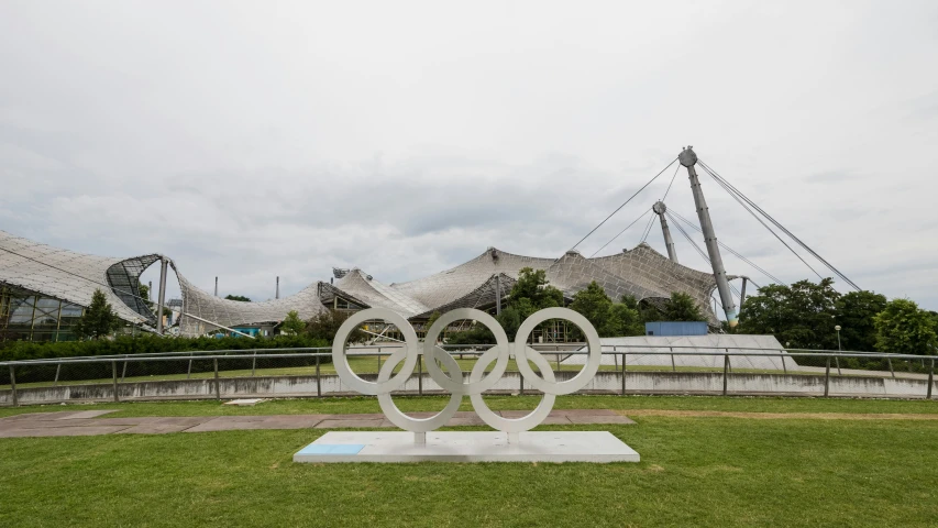 a sculpture in a park area with buildings in the background