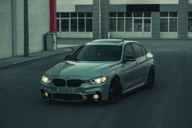 a grey bmw car with its lights on