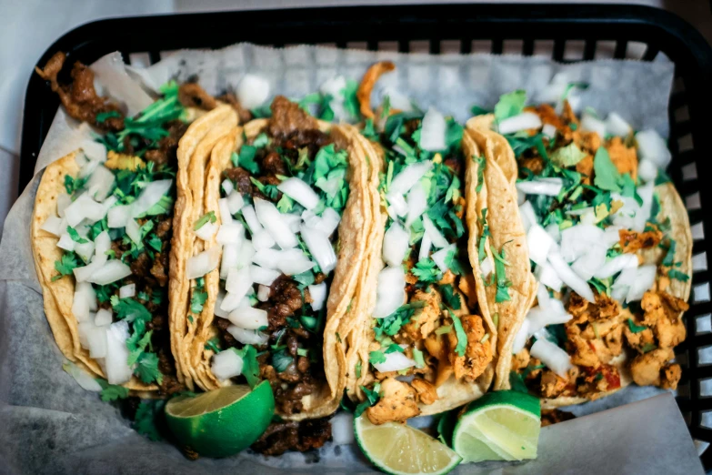 a plastic container full of three tacos and topped with cilantro