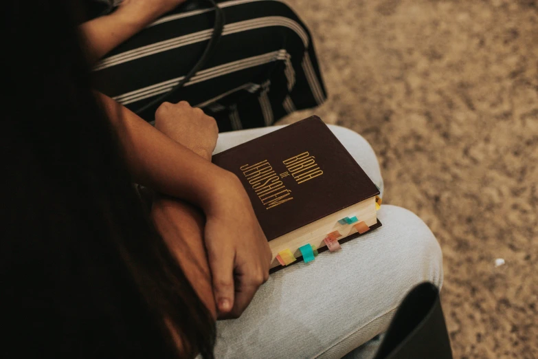 a  holding a bible while sitting in a chair