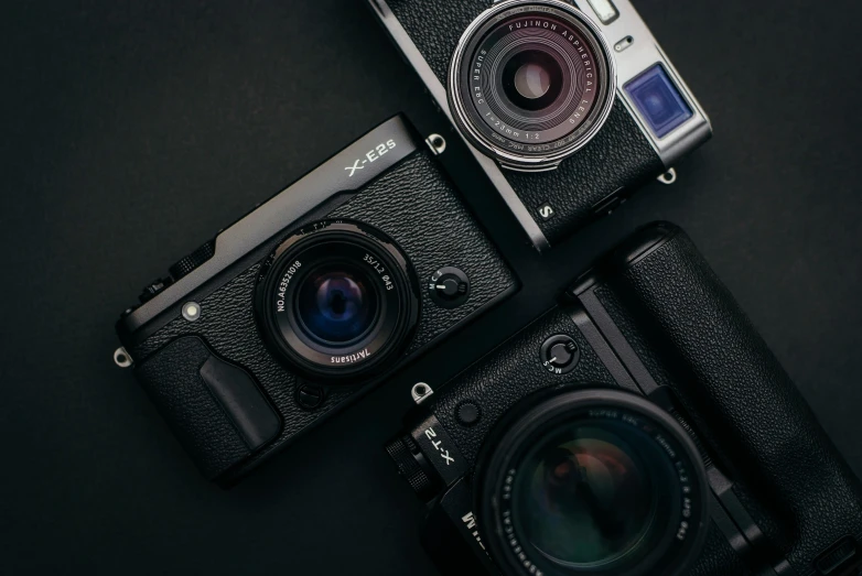 three black cameras sitting side by side, one with the camera open