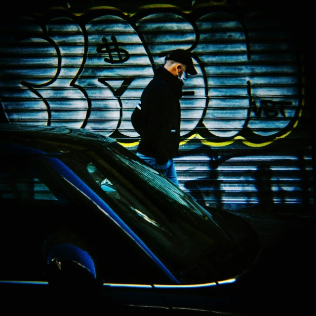 a man in black walking past a car