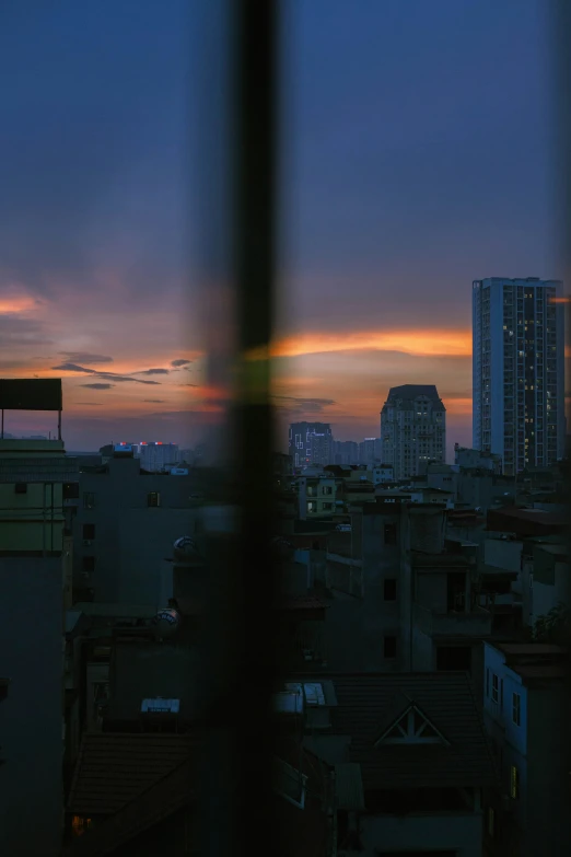 this is sunset in city buildings seen through a fence