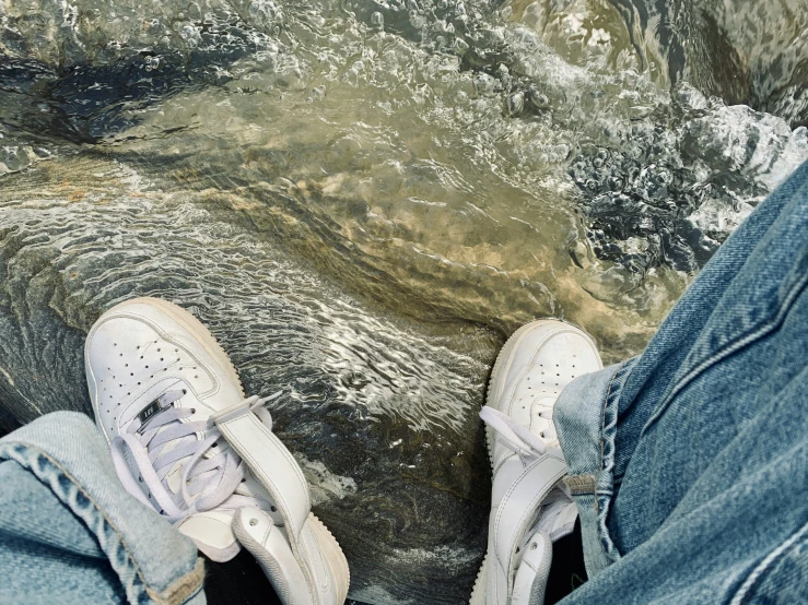 two people standing on rocks near the water