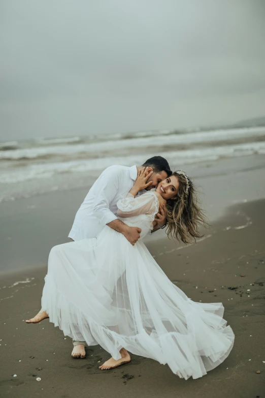 newly married couple kissing on the beach on a cloudy day