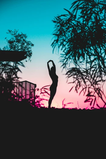 a person doing yoga with their arms up in front of a tree