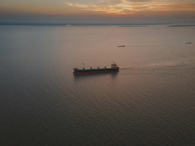 a small boat floating in the ocean during a sunset