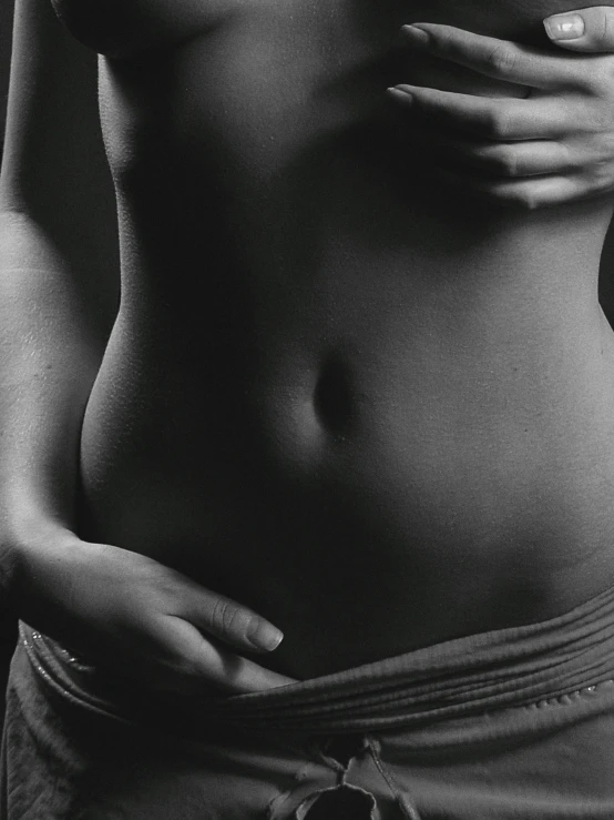 a woman holds her  with her right hand while standing against the wall