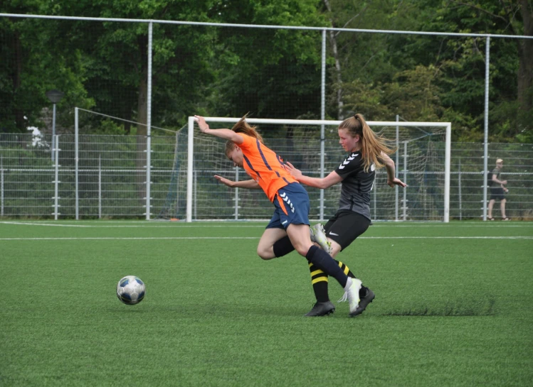 a couple of girls kicking around a soccer ball