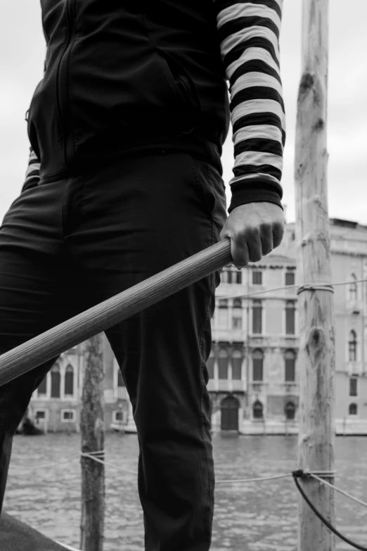 black and white image of man with long skateboard on pier