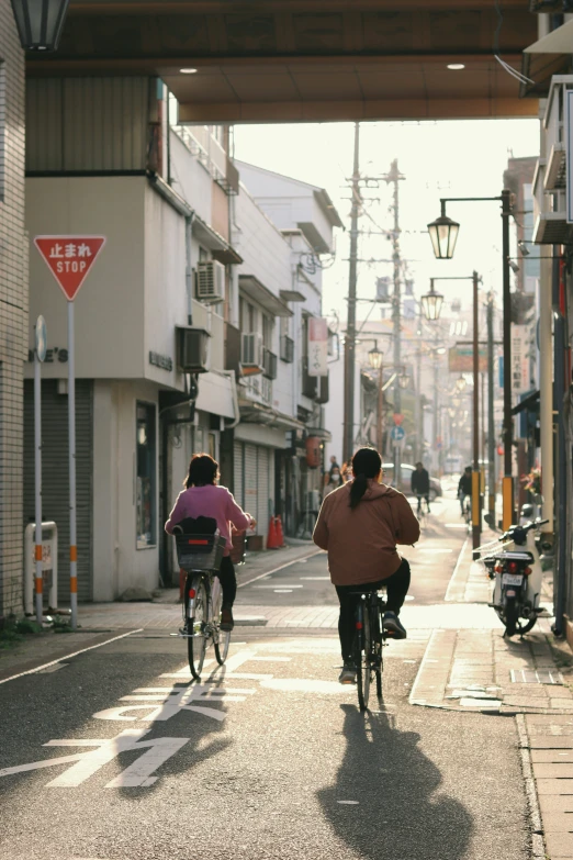 two people riding bicycles down a city street