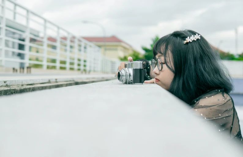 a woman leaning against the wall and taking a picture with her camera